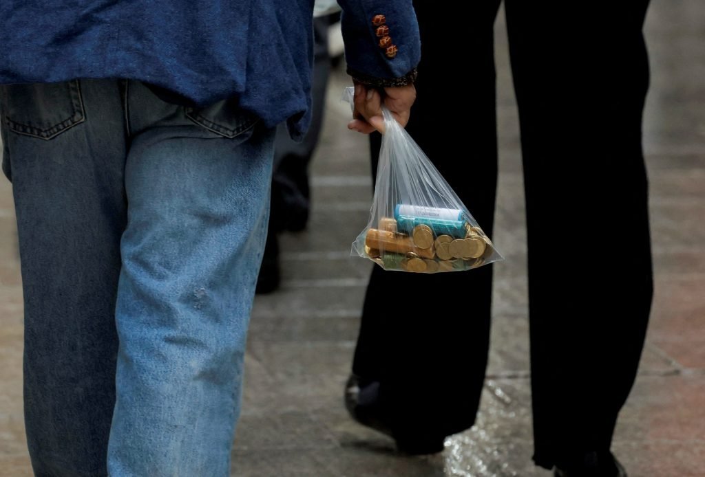 Un hombre lleva una bolsa de plástico con nuevas monedas de euro en una calle de Ronda,España, el 15 de noviembre de 2022. Foto: REUTERS/Jon Nazca